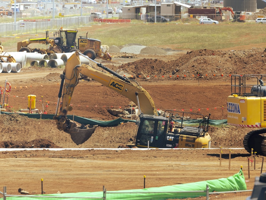 A tracked excavator parked on an open field of turned soil at a clearing site.